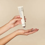 Hand holding a skincare product with a beige background