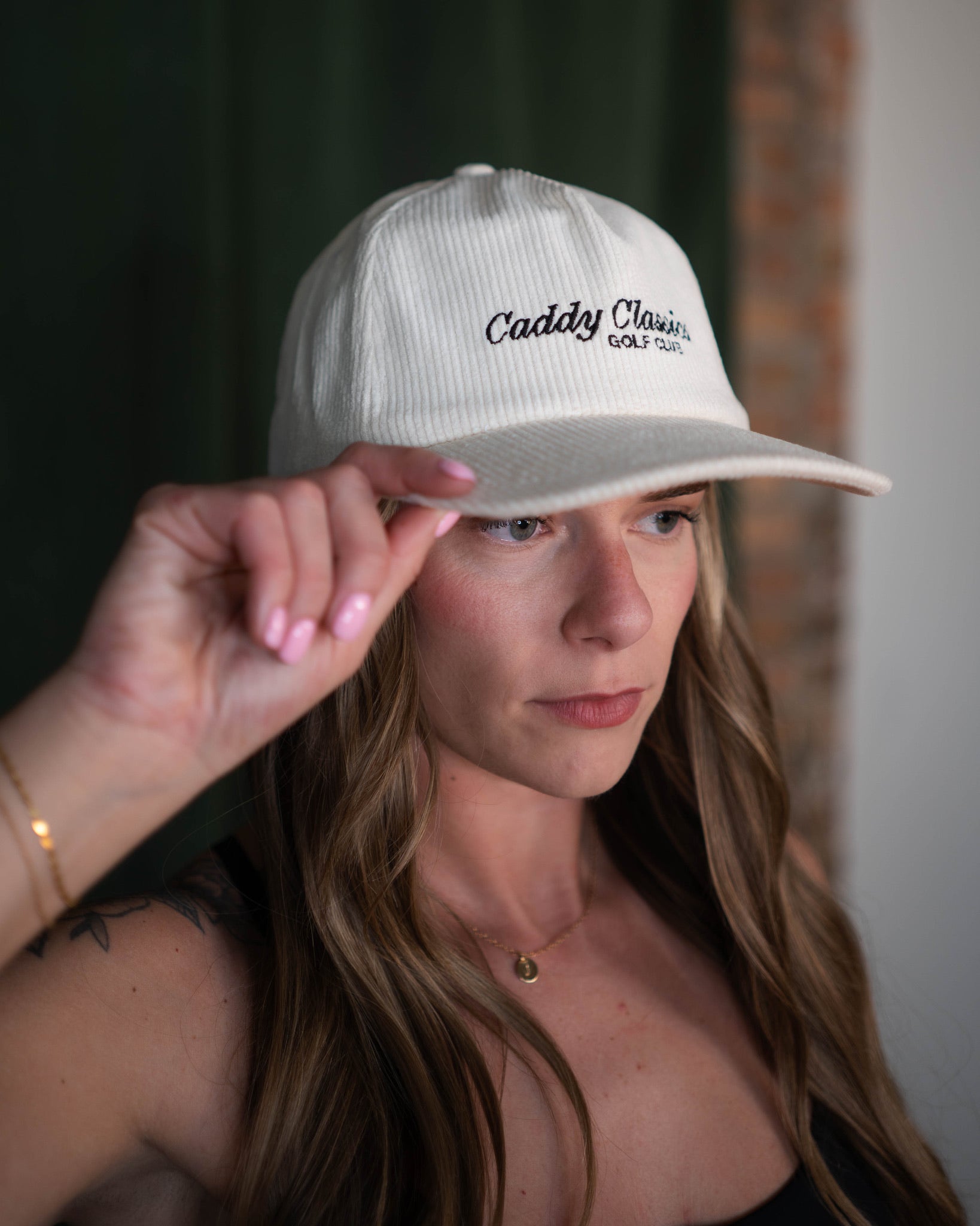Person wearing a white cap with text, holding it up to their head.