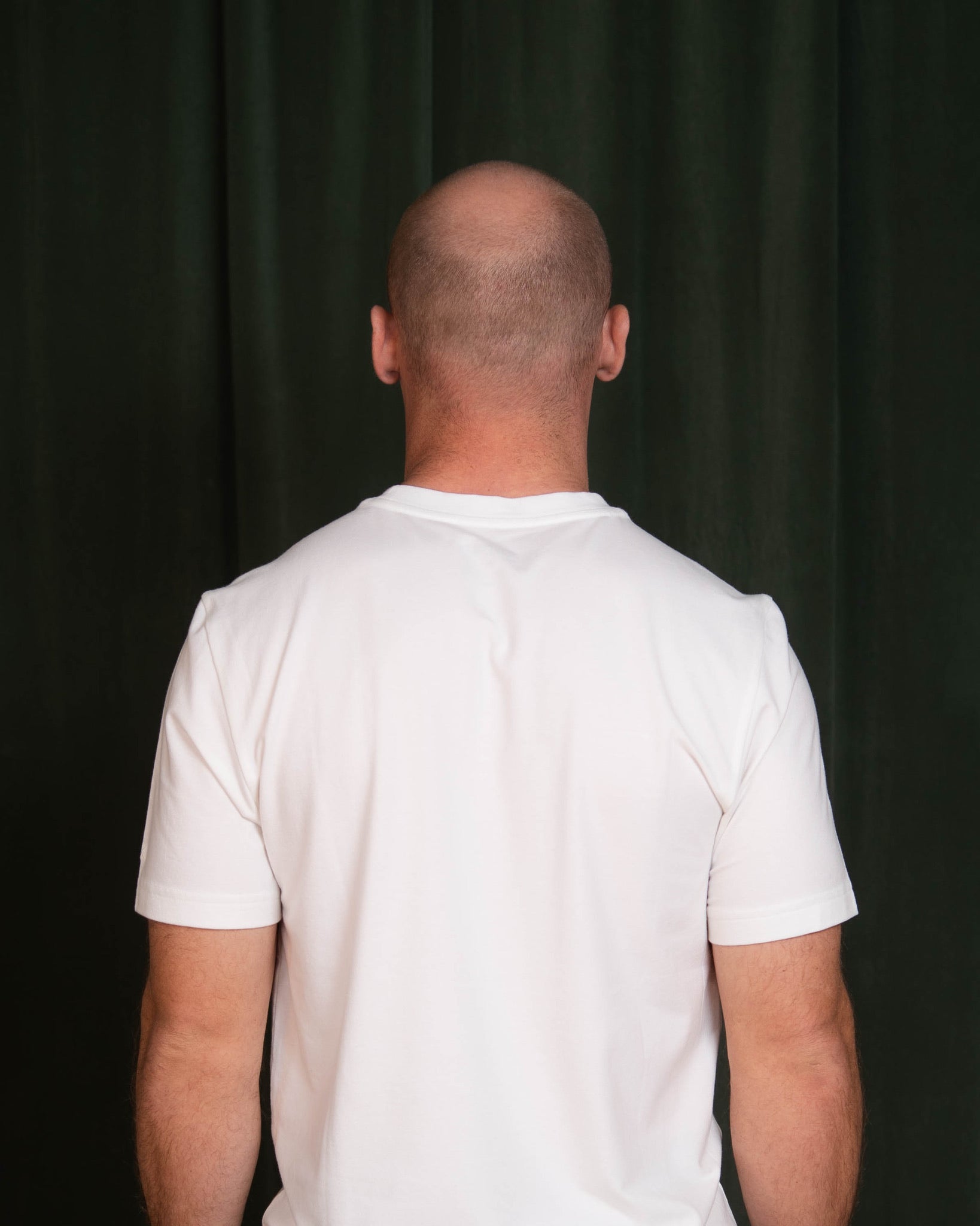Person wearing a white t-shirt against a black background
