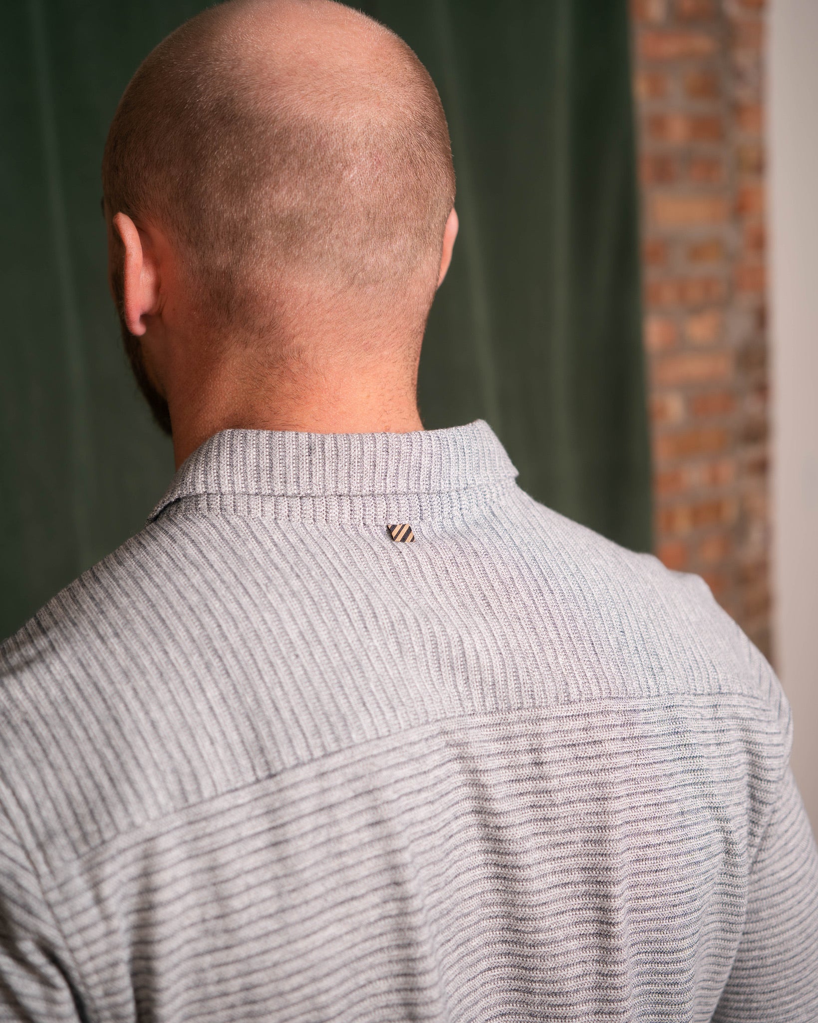 Back view of a person wearing a gray sweater with a blurred background