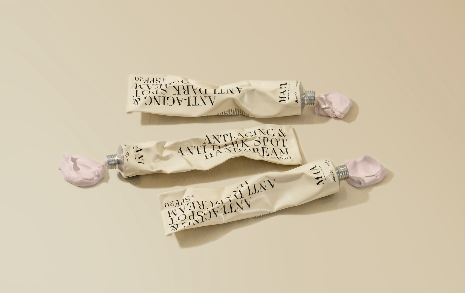 Three tubes of 'Hand Cream' on a beige background