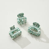 Set of green and white patterned hair ties on a white background