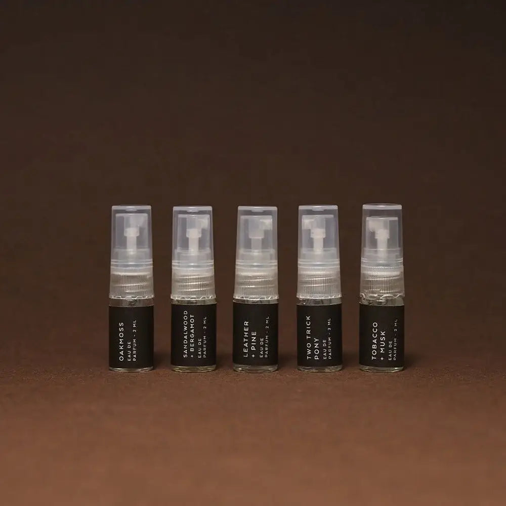 Five small spray bottles with black labels on a brown background