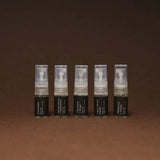 Five small spray bottles with black labels on a brown background