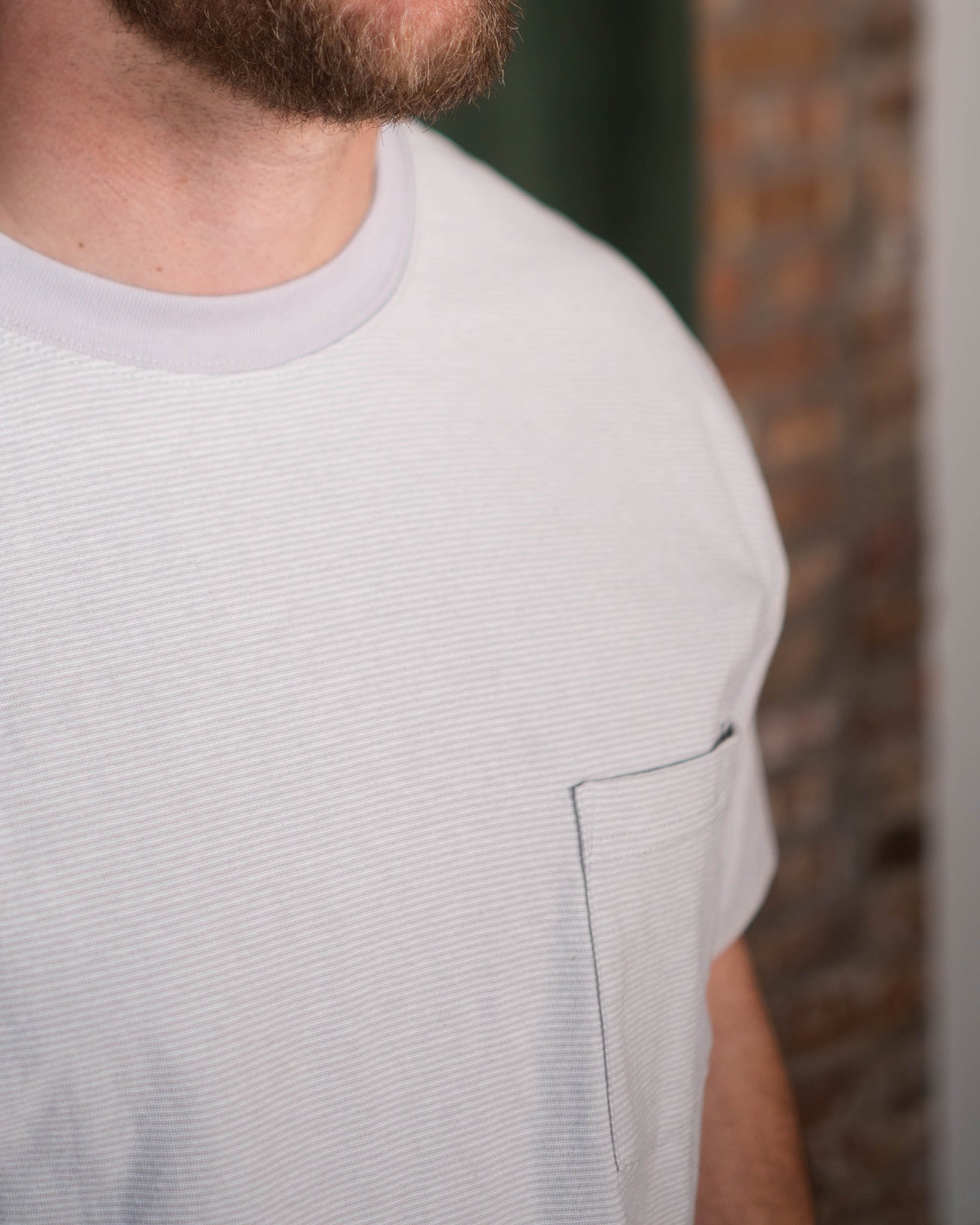 Close-up of a person wearing a light gray t-shirt with a blurred background