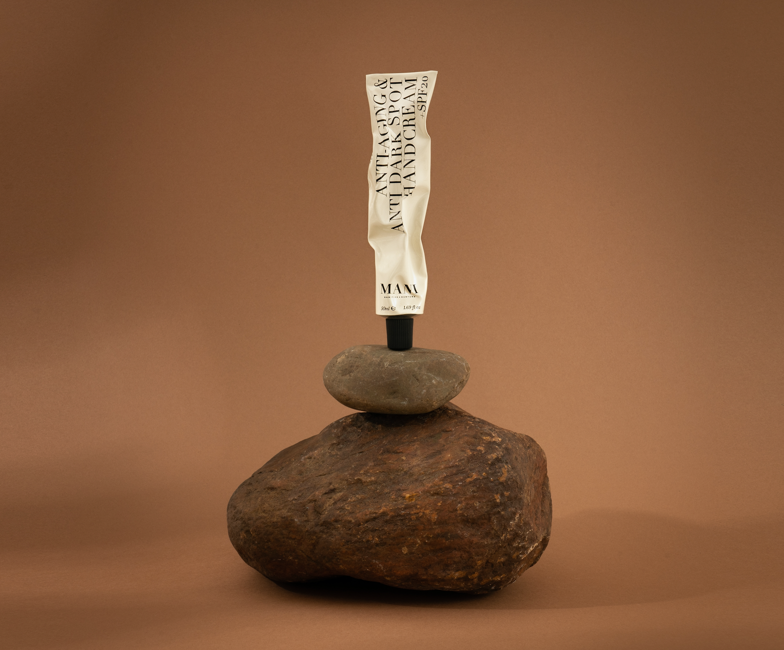 Tube of cream balanced on a rock against a brown background