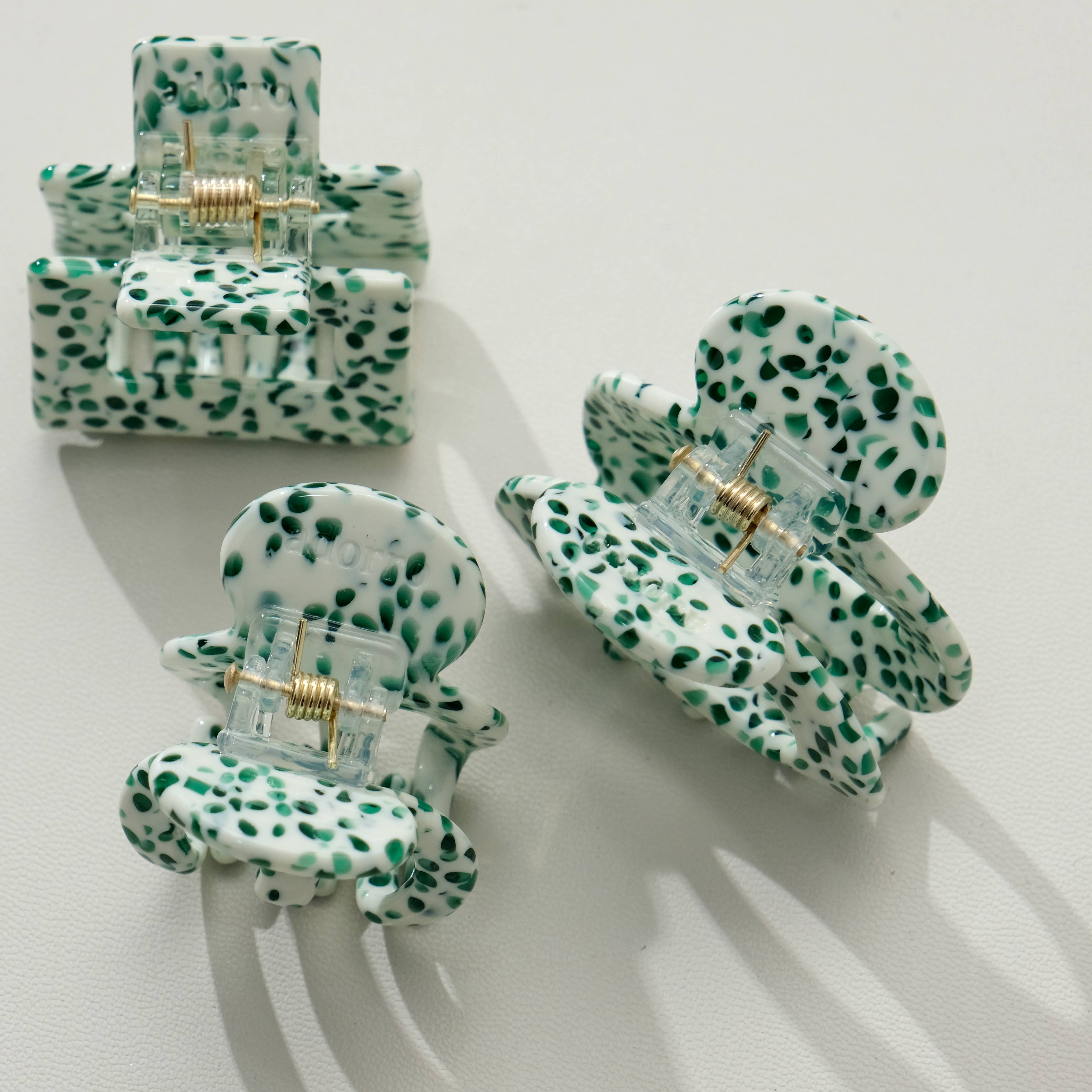 Set of three green and white patterned hair clips on a light background