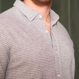 Close-up of a person wearing a gray striped shirt against a green background