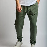 Person wearing green cargo jogger pants and white sneakers on a plain background
