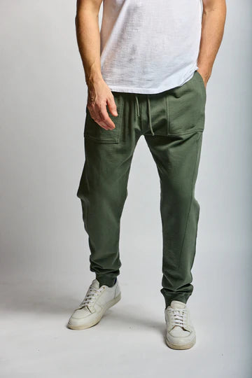 Person wearing green cargo jogger pants and white sneakers on a plain background