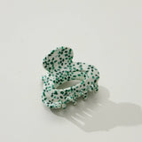 Green and white spotted hair clip on a light gray background