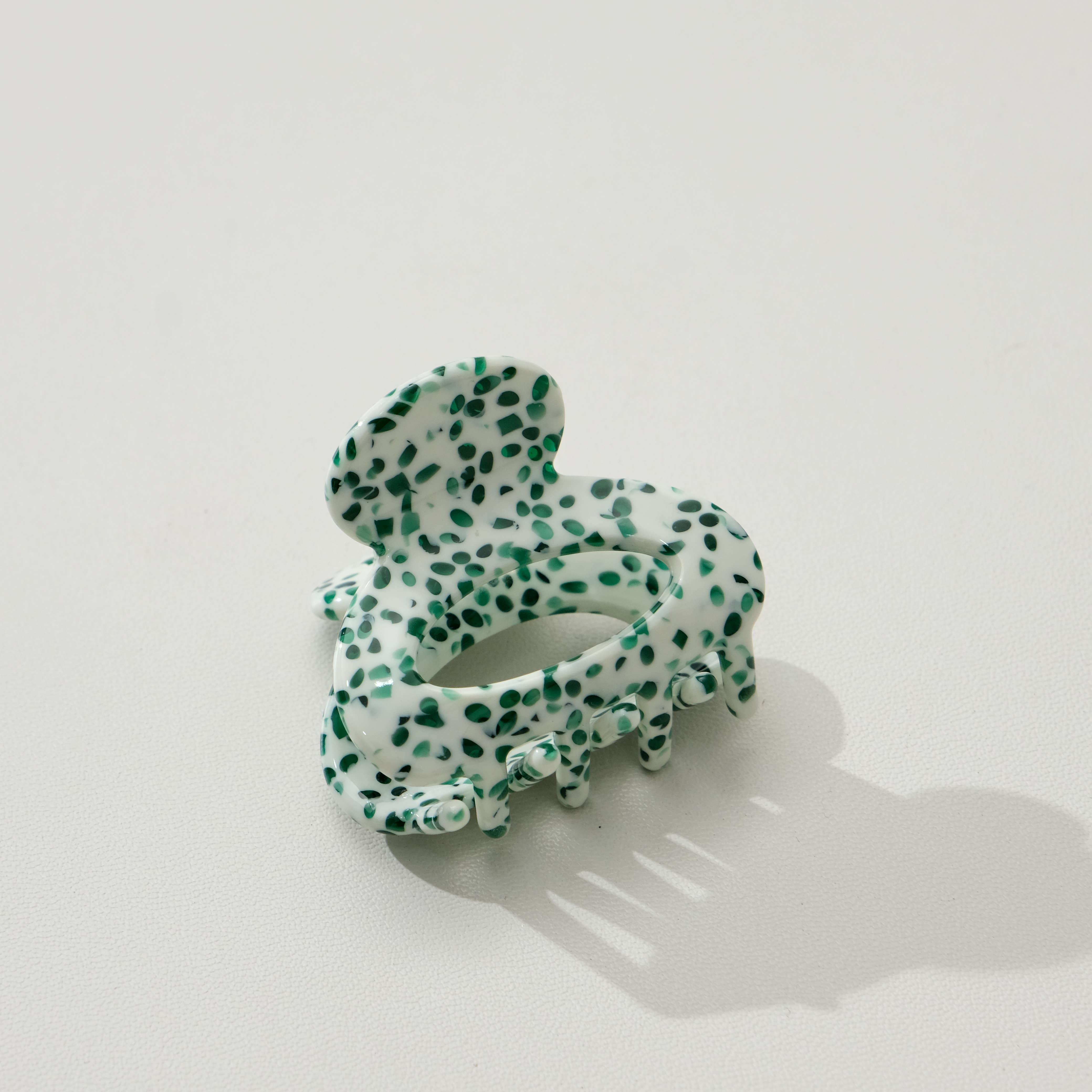 Green and white spotted hair clip on a light gray background
